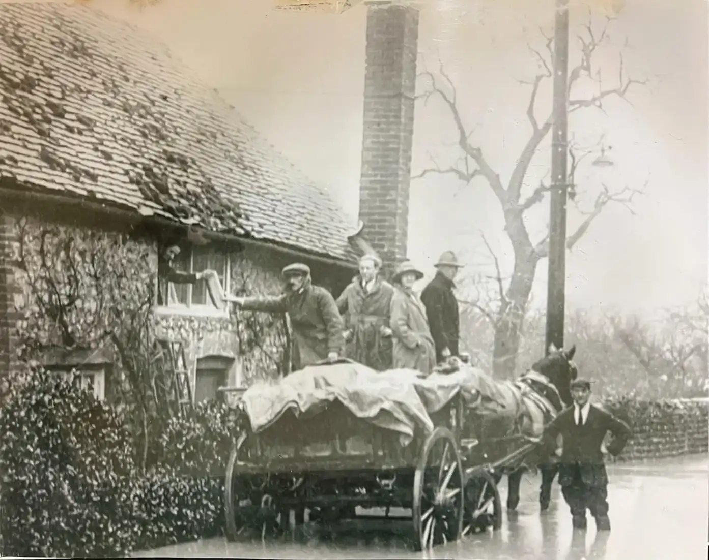 A group of men standing next to a horse drawn carriage.